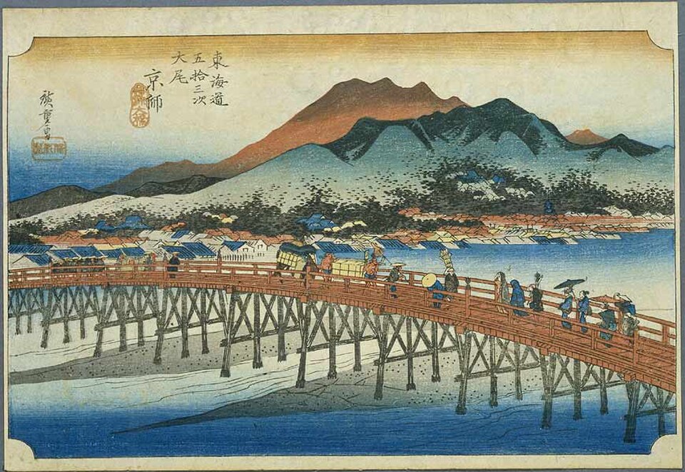 Woodblock print showing people crossing a wooden bridge over a river with a town and mountains in the background under a partly cloudy sky—a vivid glimpse into Asian history that captures moments of innovation in history through traditional artistry.